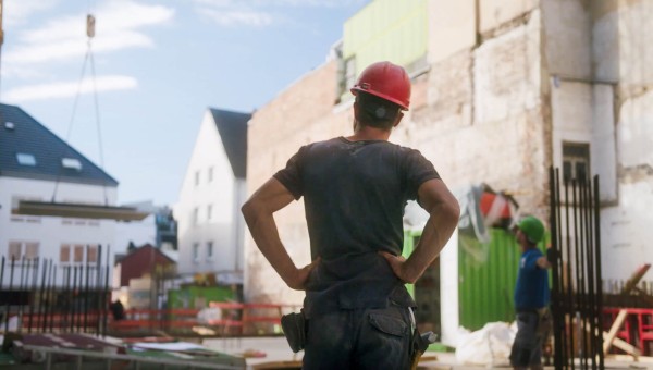 Bauleiter und Polier stehen in Sicherheitskleidung auf der Baustelle und betrachten die Baustelle im Hochbau. Die Bausoftware Vorteile liegen in den Automatisierungen auf der Baustelle.