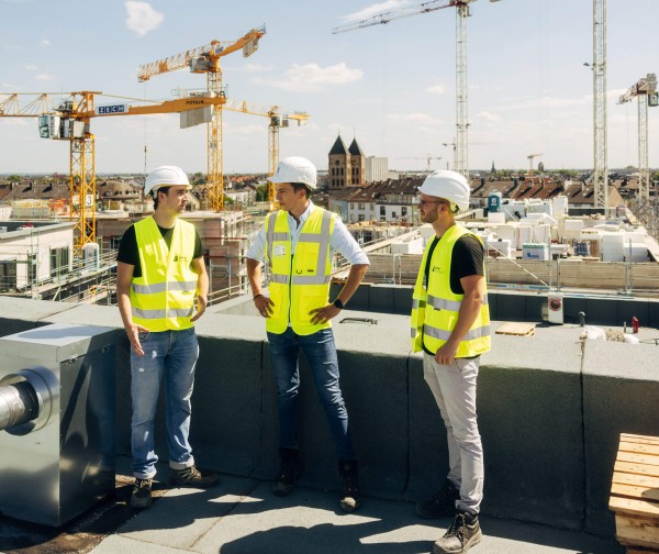 Drei Personen unterhalten sich auf der Baustelle über spannende Startup Job im ConTech Startup für die Bauindustrie.